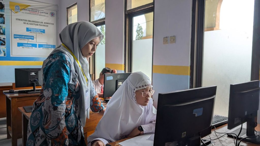 Guru berhijab mendampingi siswa di lab komputer