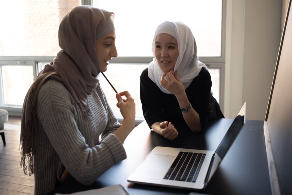 Mahasiswi muslimah berhijab belajar bersama menggunakan laptop